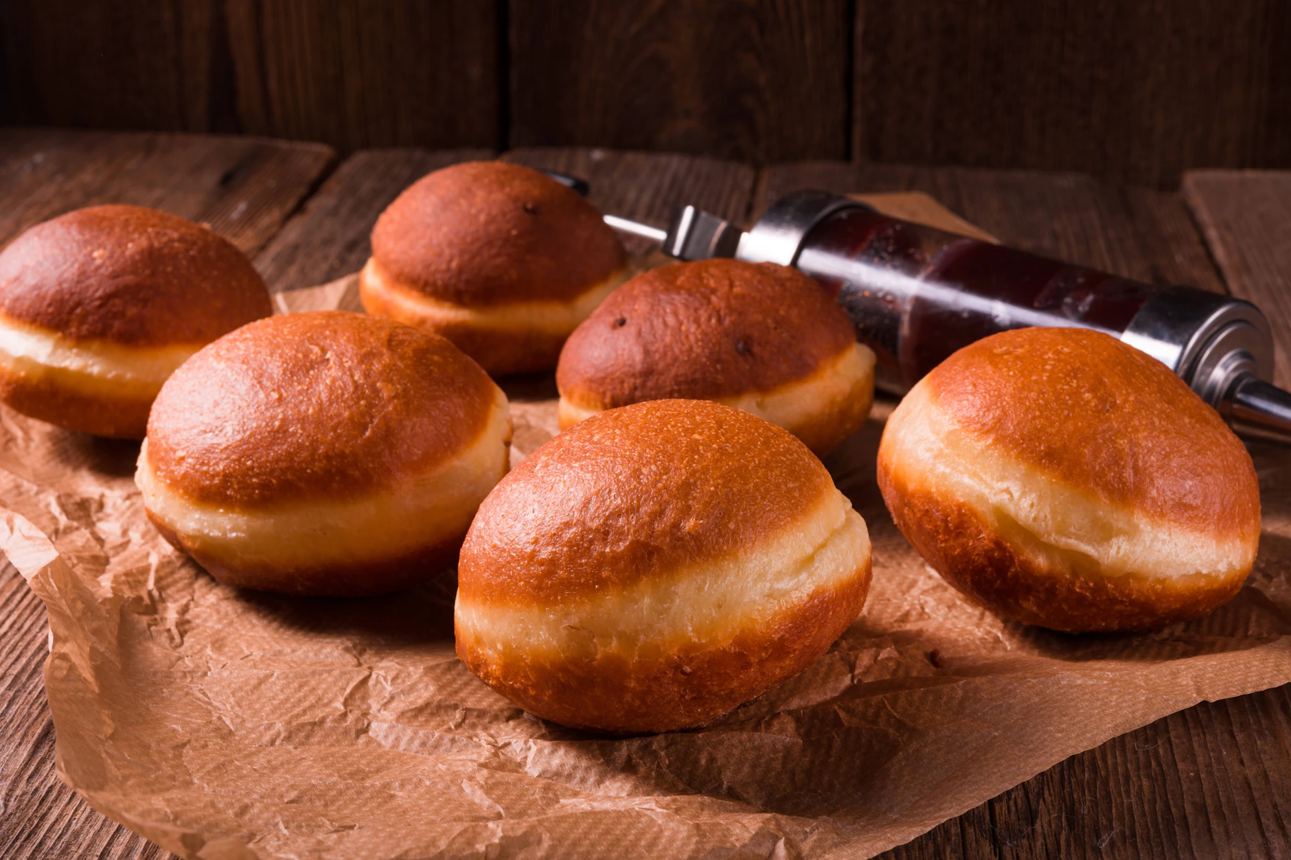 Mit einer Gebäckspritze mit Marmelade in den fertig gebackenen Berliner Pfannkuchen injiziert.