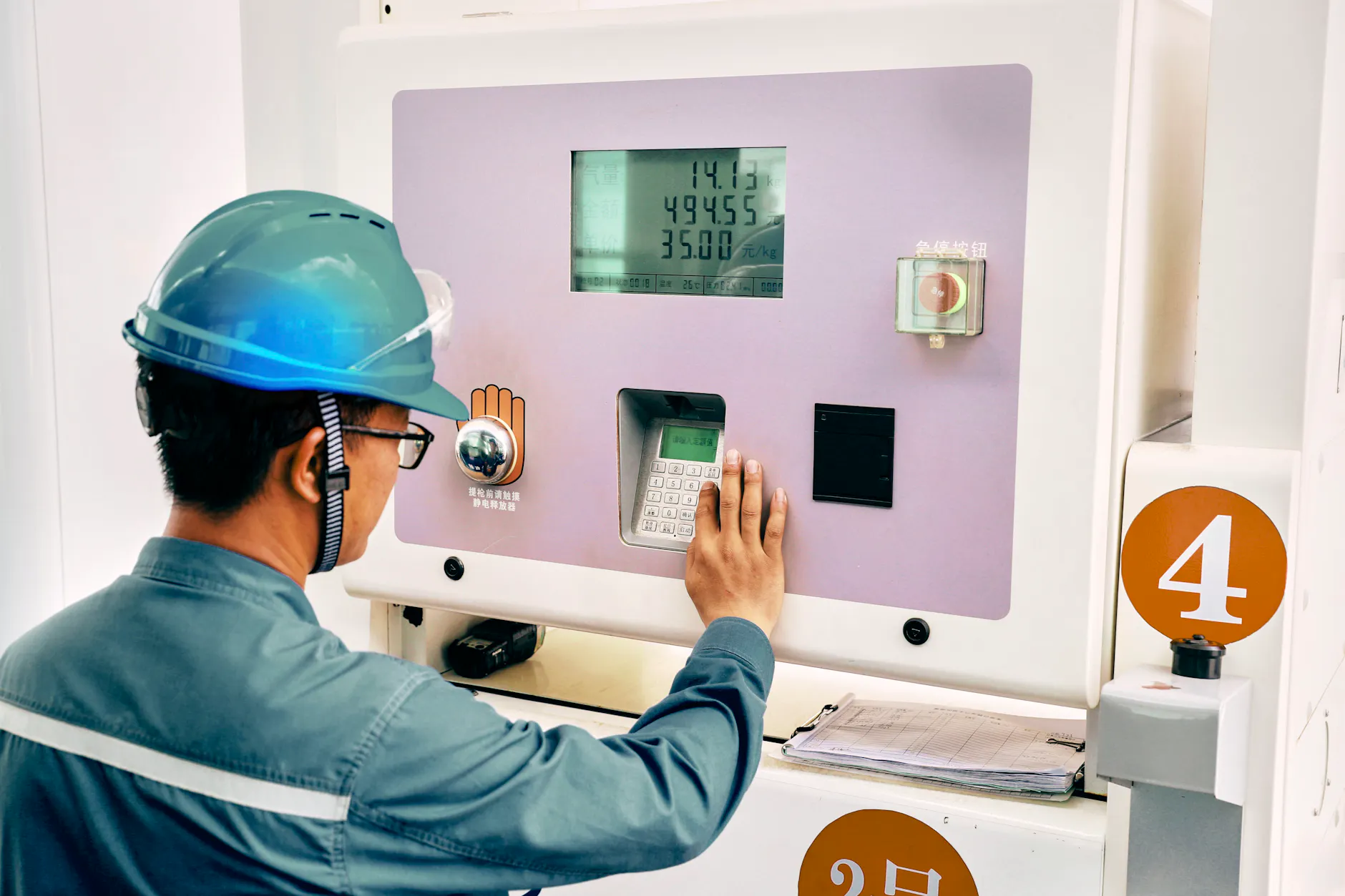 Ein Mitarbeiter der Qinjdao Refining & Chemical Company bedient an einer Wasserstofftankstelle das Tastenfeld einer Zapfsäule.