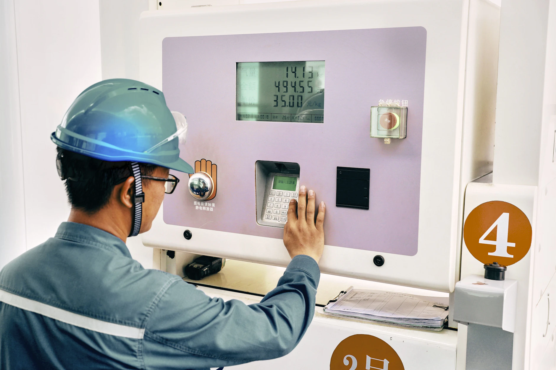 Ein Mitarbeiter der Qinjdao Refining &amp; Chemical Company bedient an einer Wasserstofftankstelle das Tastenfeld einer Zapfsäule.