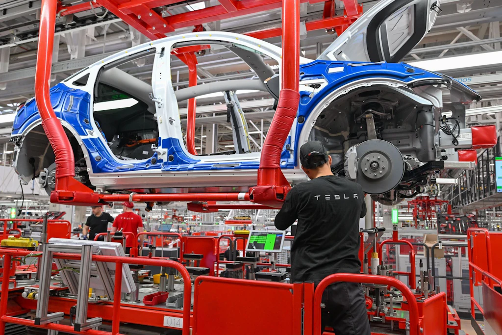 Ein Mitarbeiter montiert im Tesla-Werk in Grünheide an einer Fertigungslinie für Elektrofahrzeuge vom Typ Model Y.