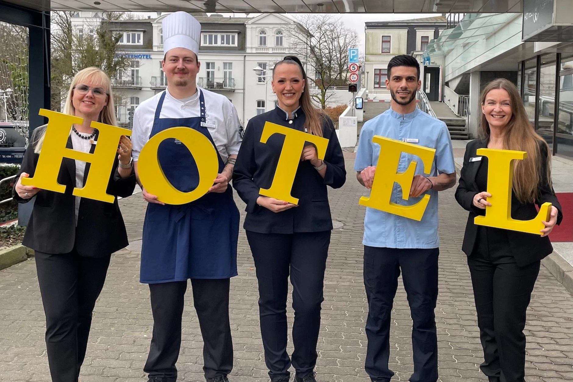 Mitarbeiter des Hotel Neptun mit den historischen Buchstaben: Logis-Managerin Kerstin Pingel-Scheydt, Chef de Partie Simon Wingenfeld, die stellvertretende Restaurantleiterin Lisa Wellsandt aus dem Café Panorama, Omar Sabreen aus dem Housekeeping und PR-Chefin Silke Greven.