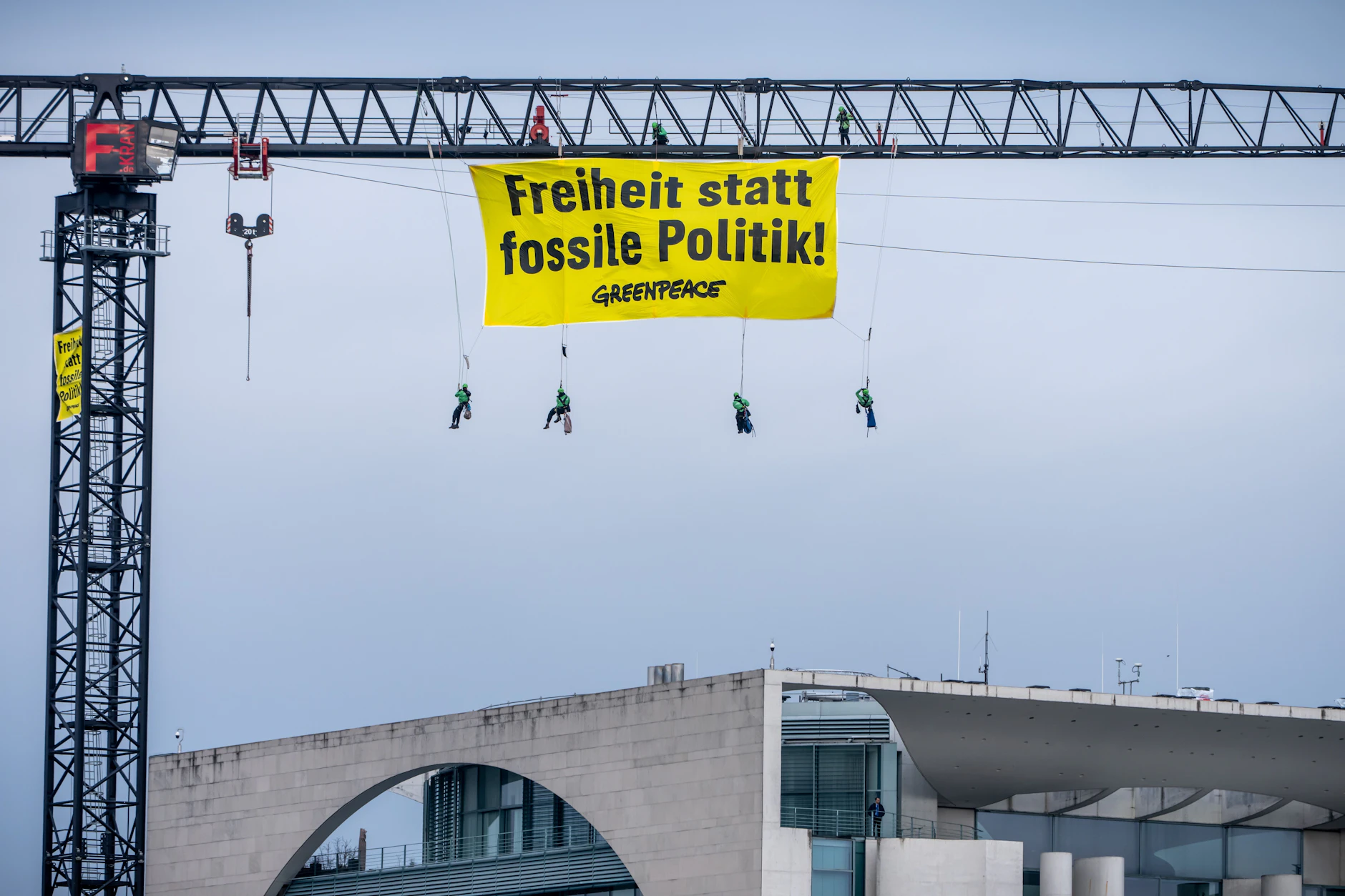 Berlin: Aktivisten der Umweltschutzorganisation Greenpeace hängen mit einem Transparent „Freiheit statt fossile Politik“ an einem Kran auf dem Gelände des Bundeskanzleramtes.