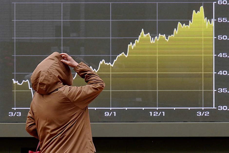 Eine Person schaut auf eine elektronische Börsentafel, die den japanischen Nikkei-Index anzeigt.