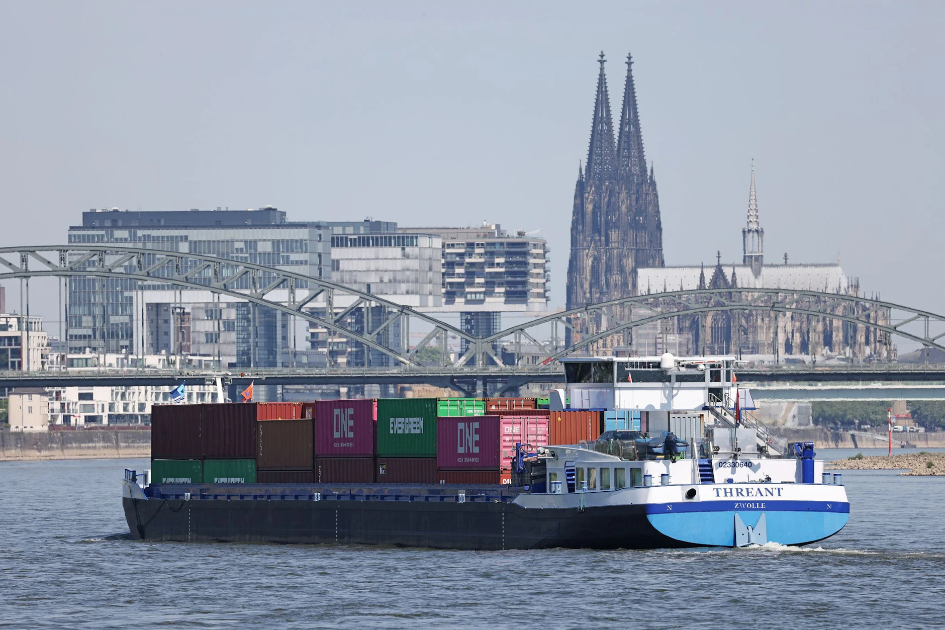 Ein Binnenschiff, mit Containern beladen, fährt in Köln vor dem Dom.