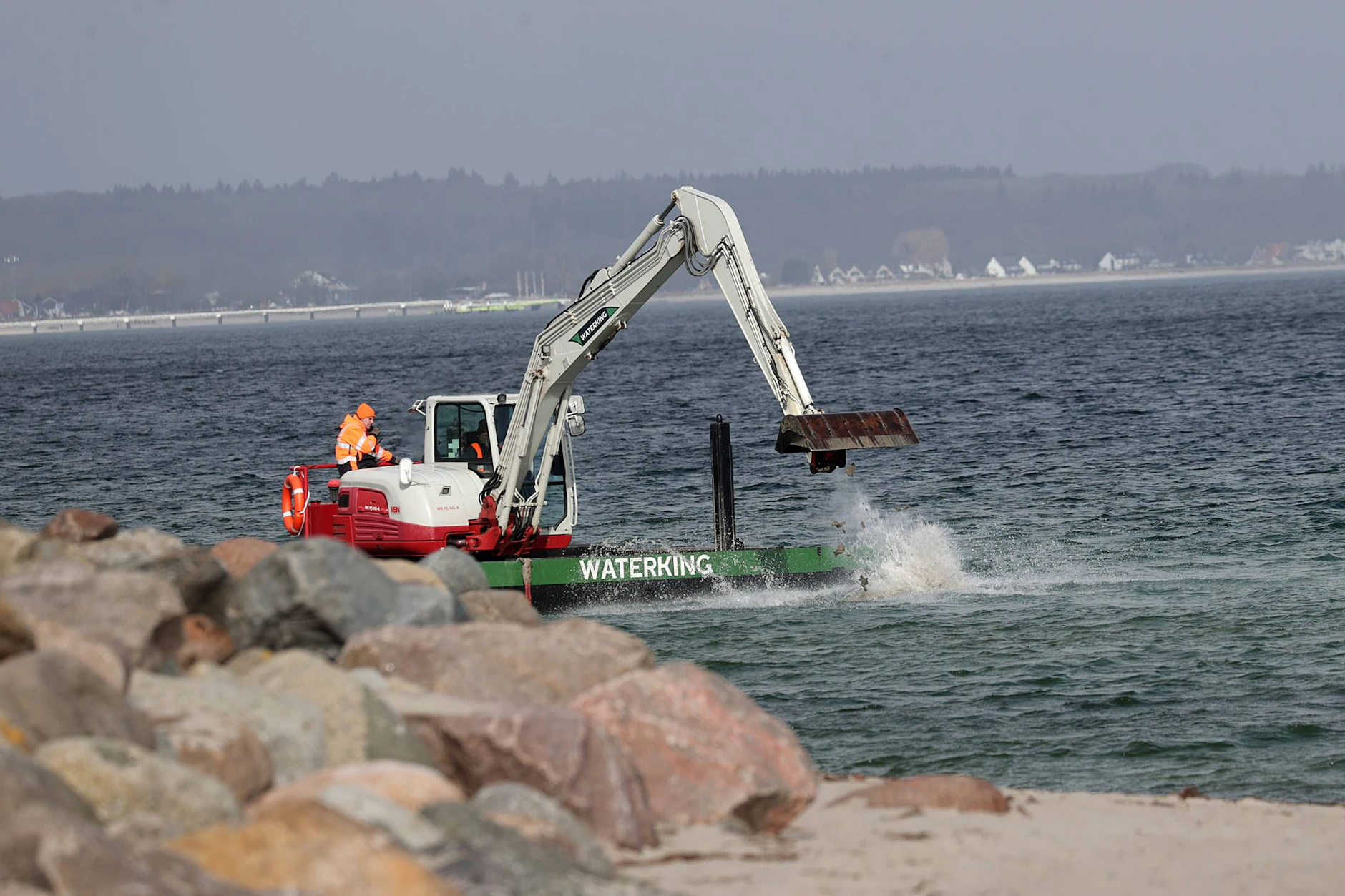 Mit schwerem Gerät: Ein Bagger versucht, eine Rinne durch die Sandbank zu graben, um dem Wal den Weg zurück ins Meer zu öffnen.