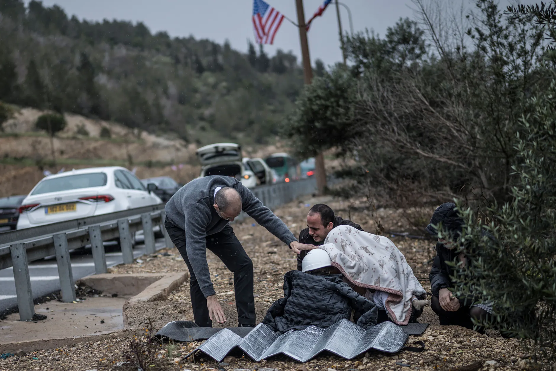 Ein Mann schützt ein Kind während eines iranischen Raketenangriffs am Straßenrand nahe Latrun.