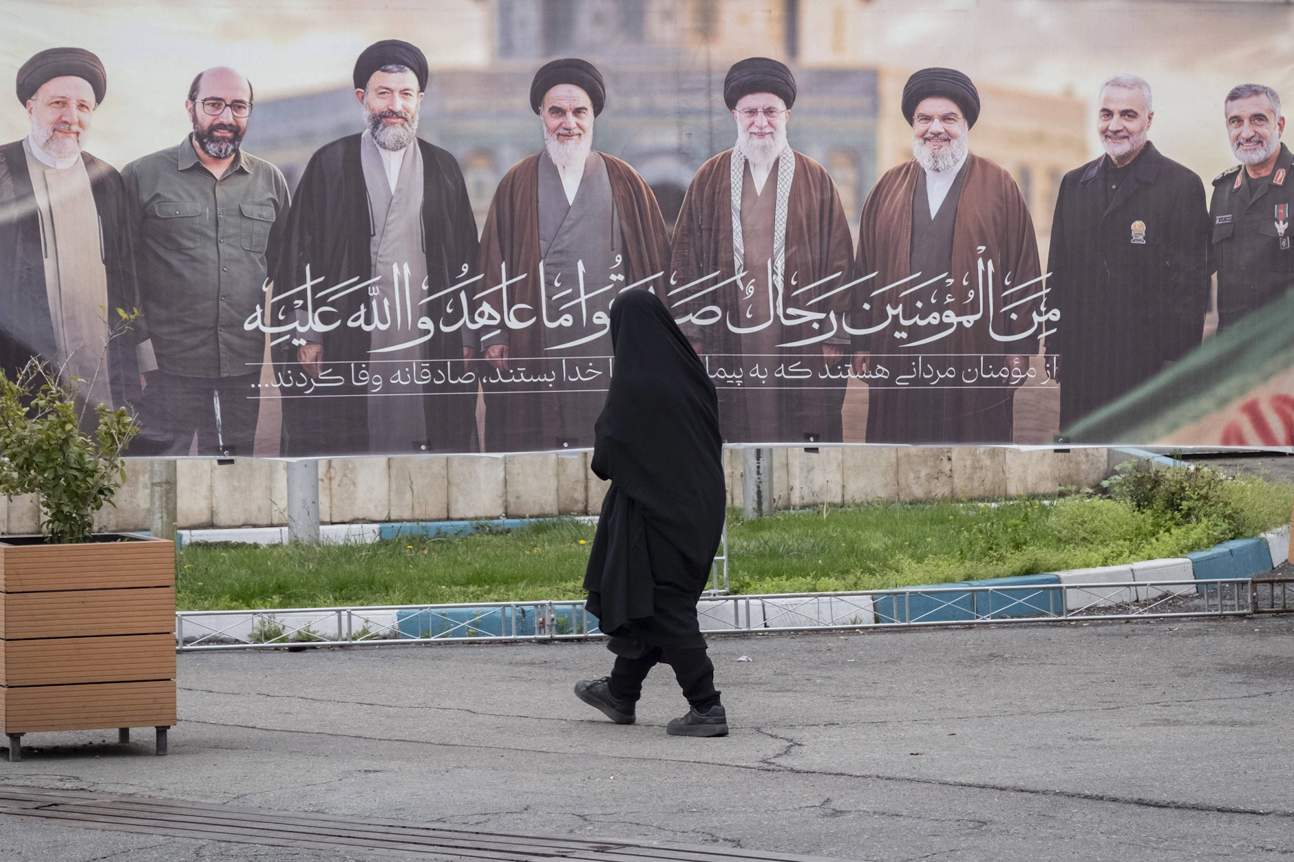 Eine Frau geht in Teheran an einem Banner mit verstorbenen Führungsfiguren vorbei, darunter Ali Chamenei, Ruhollah Chomeini, Hassan Nasrallah und Qassem Soleimani.
