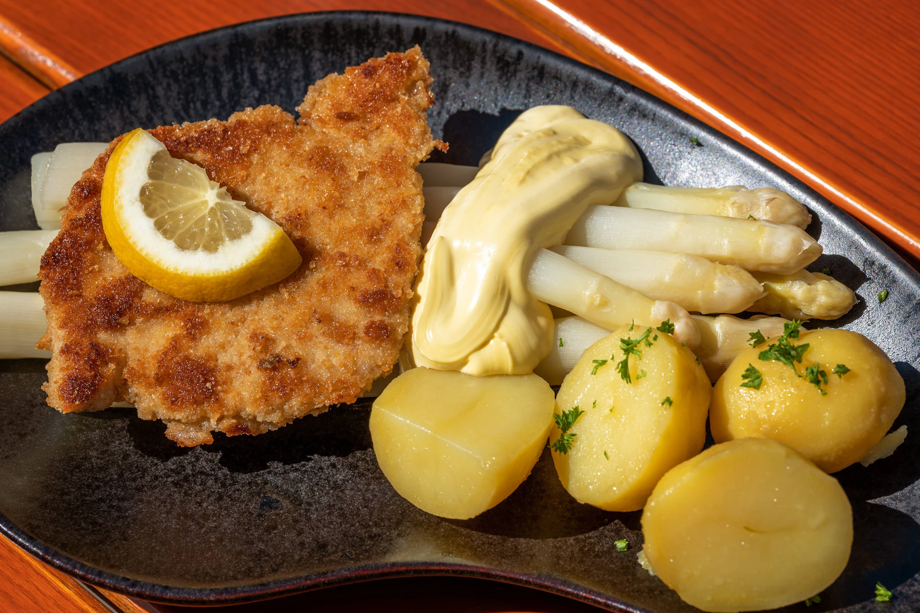 Ganz klassisch: Der weiße, gekochte Spargel wird mit Sauce Hollandaise, Salzkartoffeln und einem Wiener Schnitzel angerichtet.