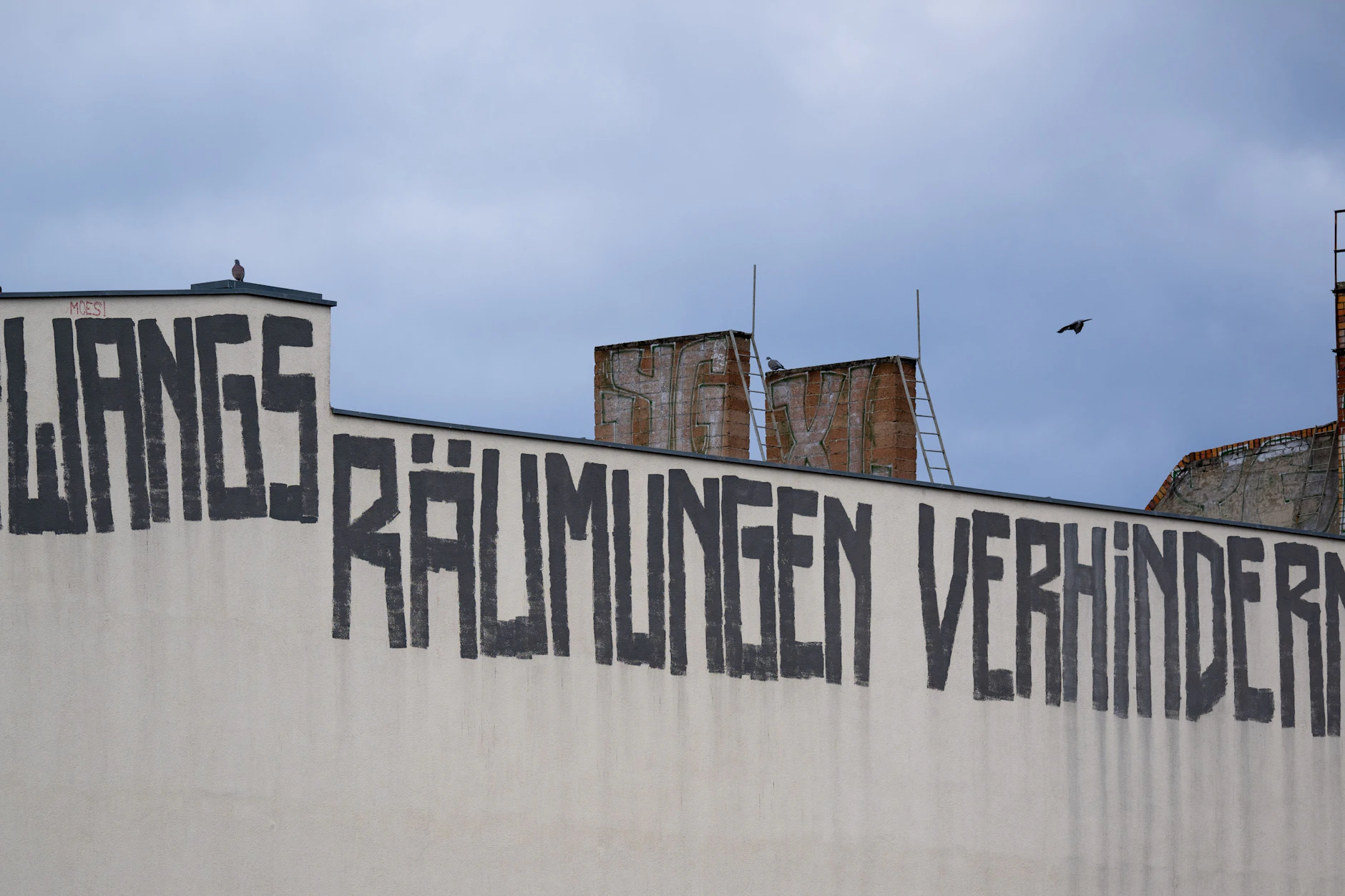 Längst ist die Wohnungsmisere im Berliner Stadtbild angekommen. Auf der Brandmauer eines Wohnhauses ist der Schriftzug „Zwangsräumungen verhindern“ zu sehen. 