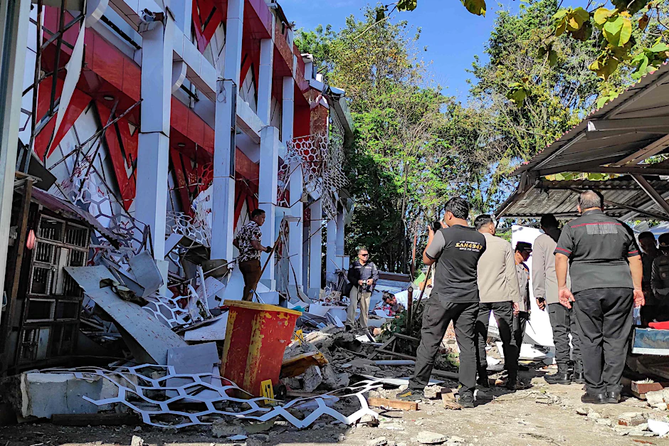 Polizeibeamte inspizieren Schäden an einem Gebäude nach dem Erdbeben in Indonesien.