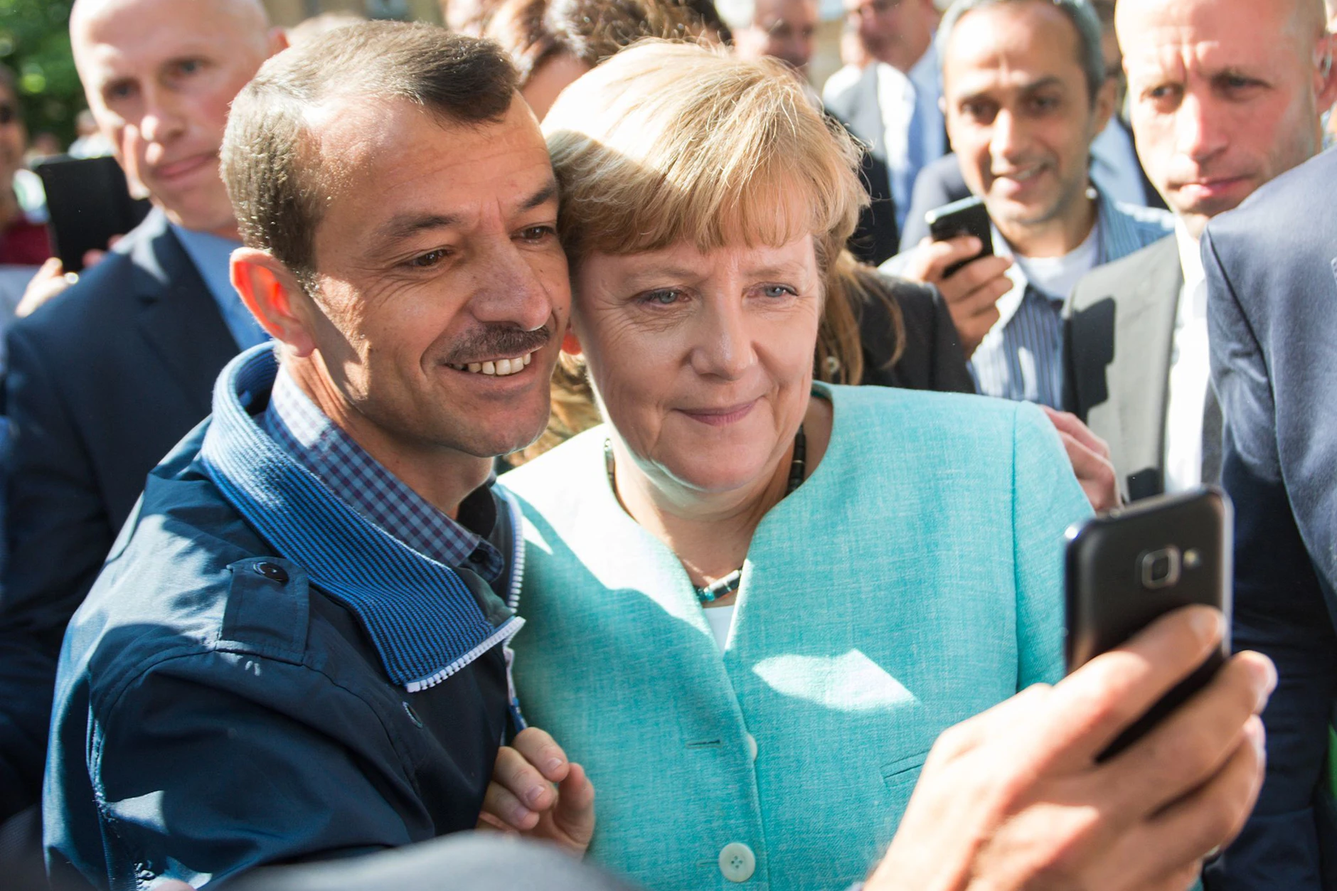 Ehemalige Bundeskanzlerin Angela Merkel (CDU) lässt sich nach dem Besuch einer Erstaufnahmeeinrichtung für Asylbewerber in Berlin-Spandau für ein Selfie zusammen mit einem Flüchtling fotografieren.