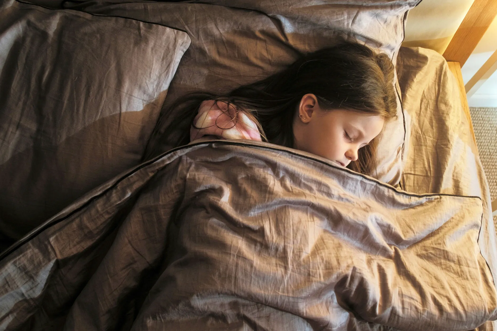 Ein Mädchen schläft von Geräuschen abgeschirmt: Viele Kinder mit ME/CFS können ihr Bett kaum verlassen.