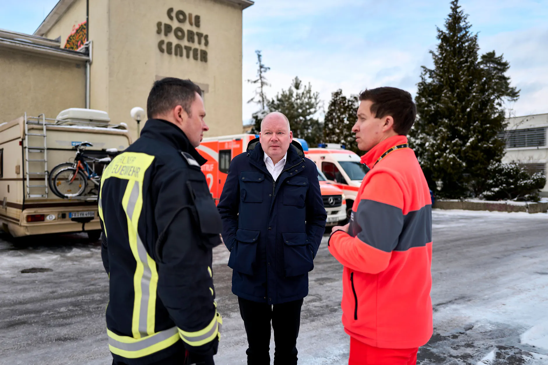 Im Jnauar 2026: Der stellvertretende Bezirksbürgermeister Tim Richter (Mitte) im Gespräch mit Einsatzkräften vor der Notunterkunft im Cole Sports Center am Hüttenweg.