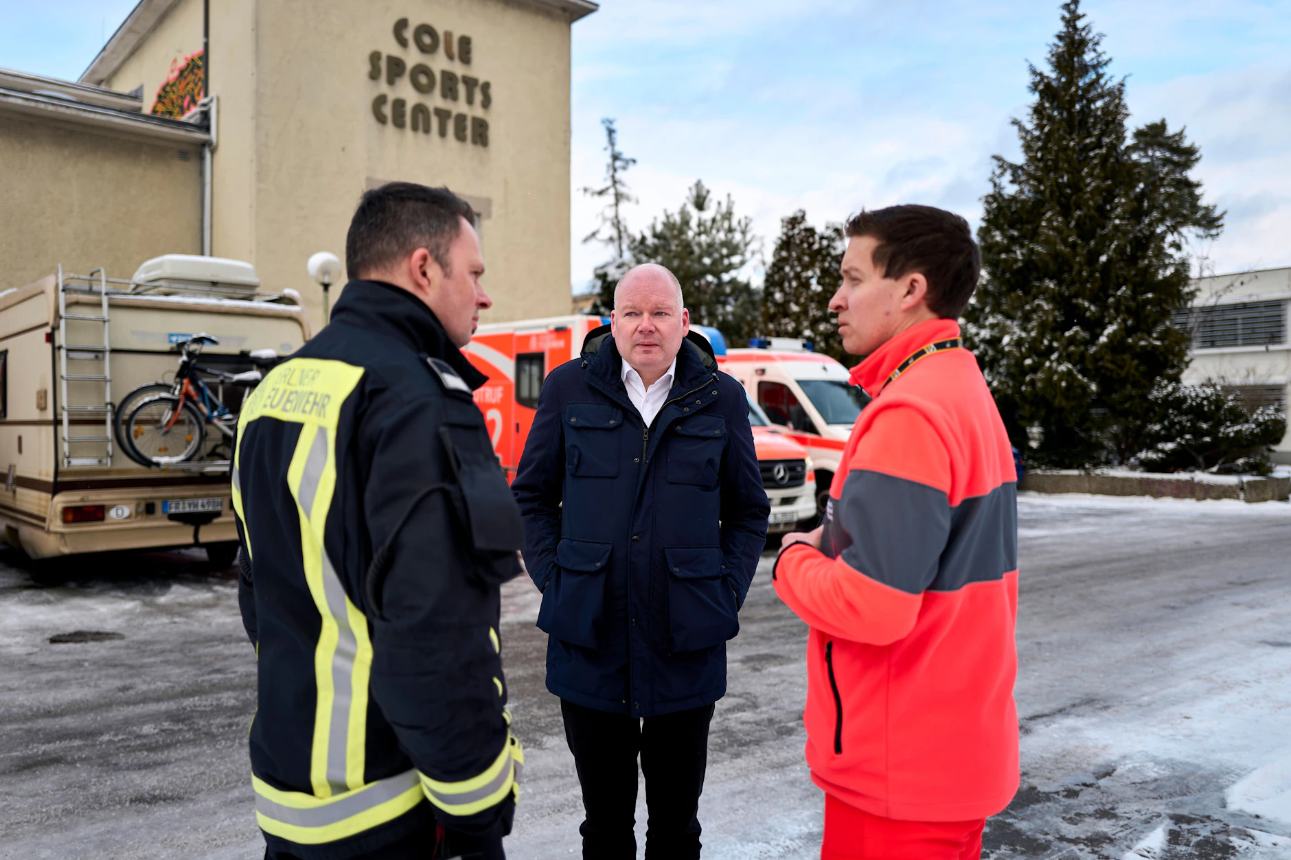 Im Jnauar 2026: Der stellvertretende Bezirksbürgermeister Tim Richter (Mitte) im Gespräch mit Einsatzkräften vor der Notunterkunft im Cole Sports Center am Hüttenweg.