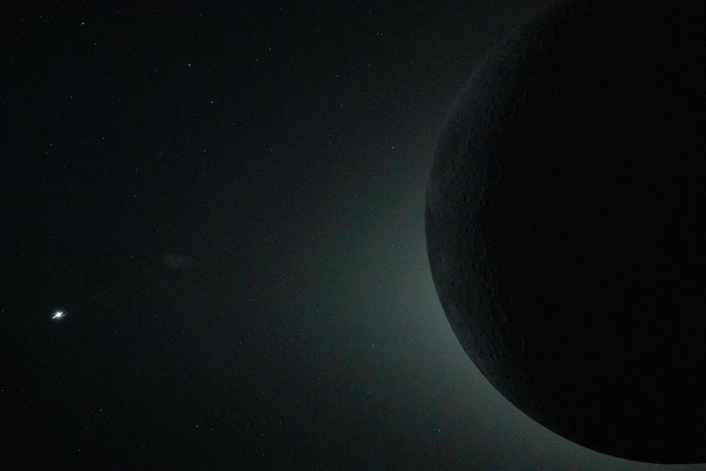 Eine totale Sonnenfinsternis. Nur ein Teil des Mondes ist im Bild zu sehen, während er die Sonne vollständig verdeckt. Unten links leuchtet die Venus.