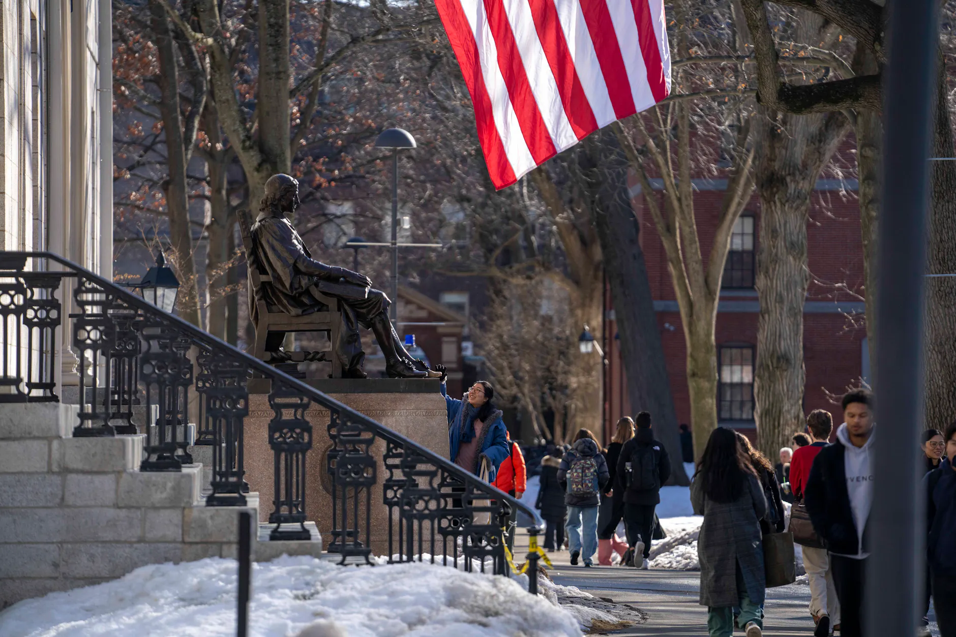 Menschen gehen an der John-Harvard-Statue vor der University Hall im Harvard Yard vorbei.