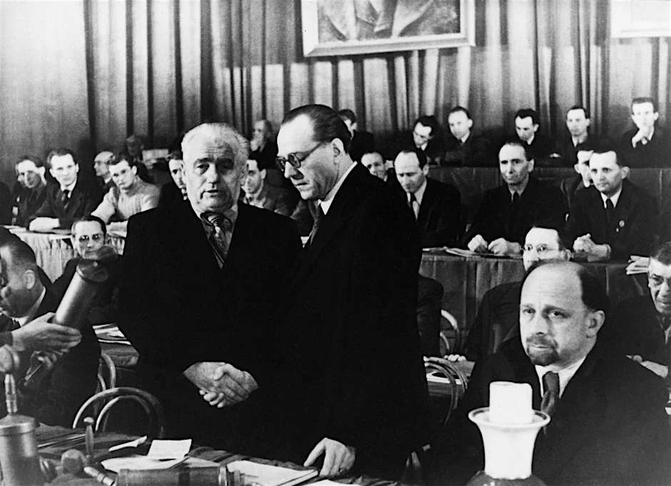 Gründung der SED durch Vereinigung von SPD und KPD am 21./22. April 1946 im Berliner Admiralspalast. Wilhelm Pieck (l.) und Otto Grotewohl, die beiden neu gewählten Vorsitzenden der SED, besiegeln die Vereinigung mit einem Händedruck. Rechts: Walter Ulbricht