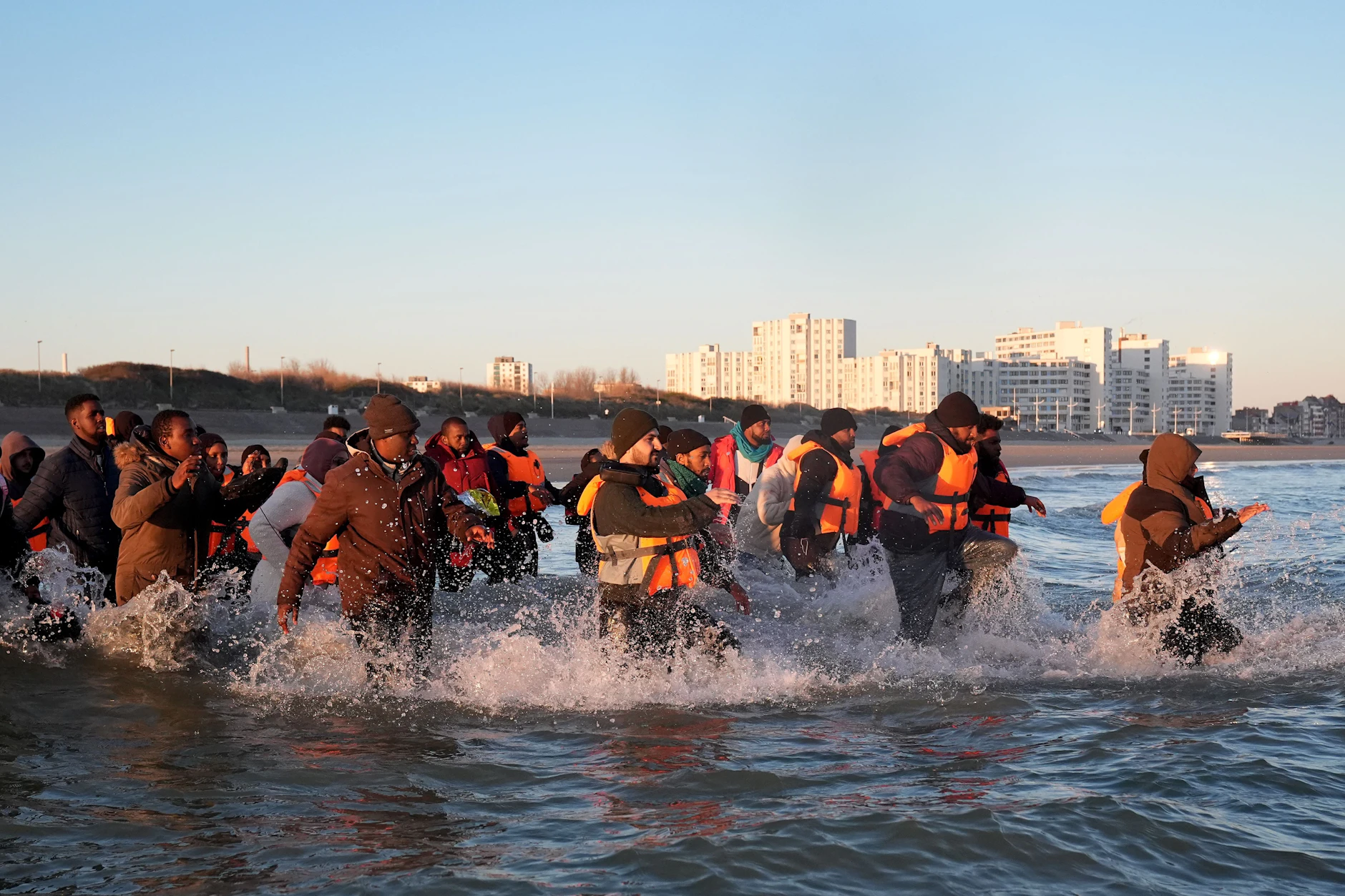 Menschen laufen ins Meer, um an Bord eines kleinen Bootes vor der Küste von Frankreich zu gelangen.