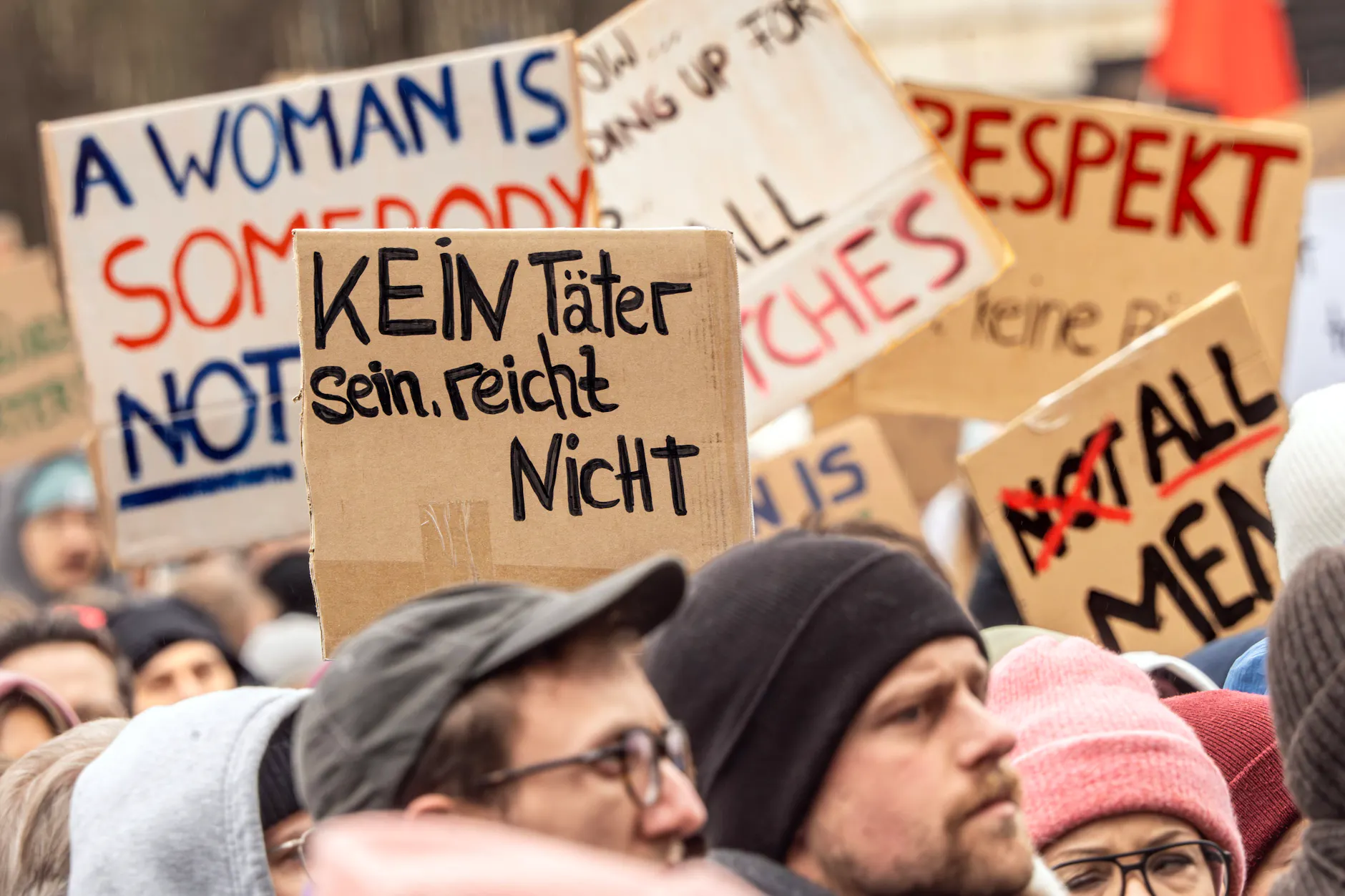 Plakate mit Aufschriften wie „Kein Täter sein reicht nicht“ sind auf einer Demonstration zu sehen.