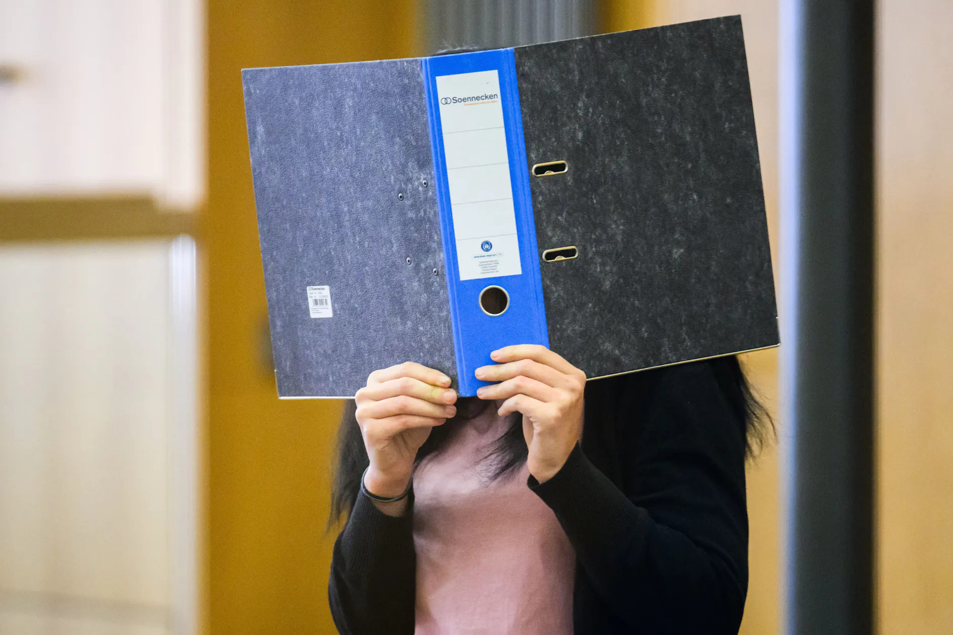 Die Angeklagte verdeckt ihr Gesicht. Die 27-Jährige soll ihren Mann mit Ameisensäure überschüttet haben, weil er sich scheiden lassen wollte.