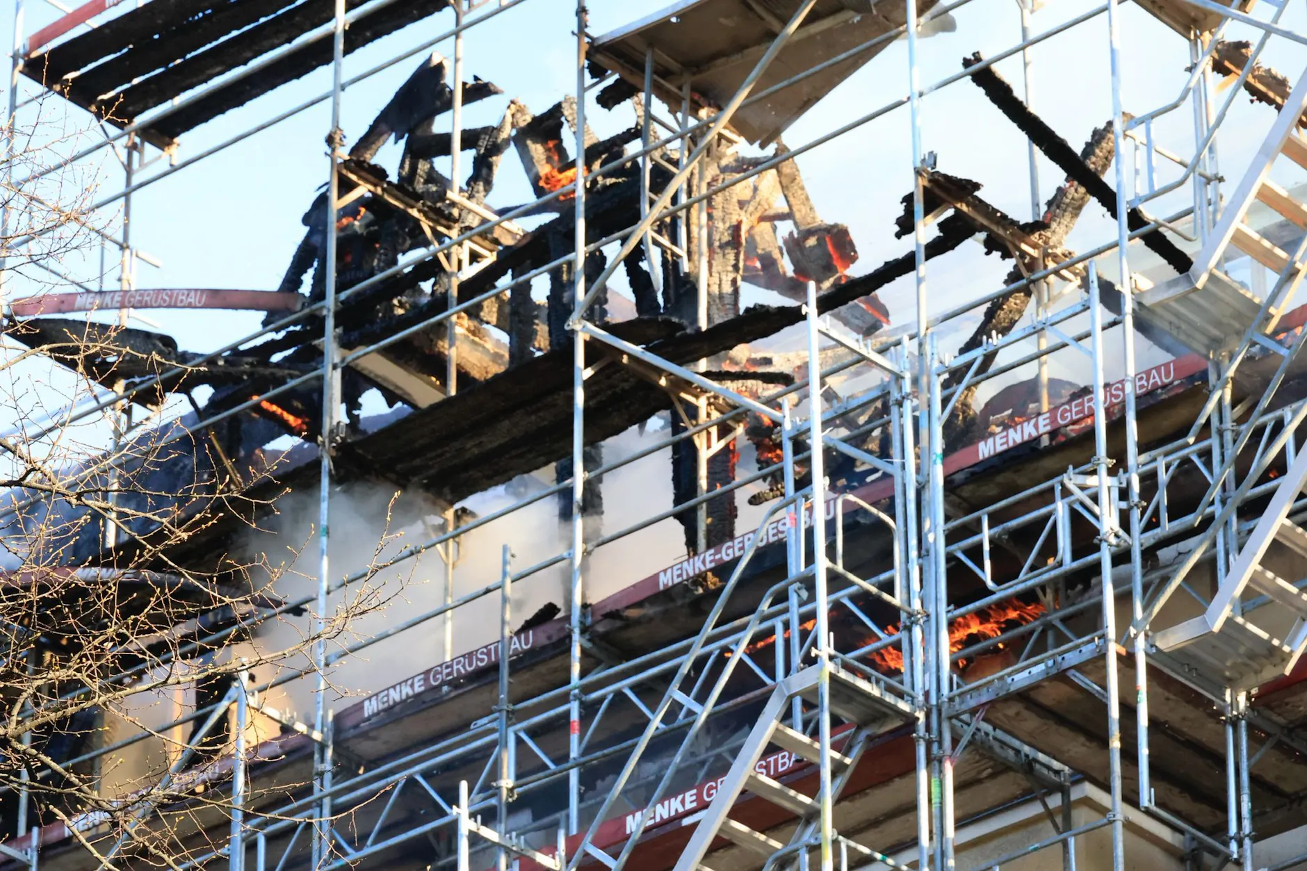 Ausgebrannter Dachstuhl eines Gründerzeithauses in Berlin-Charlottenburg: Verkohlte Balken ragen zwischen dem Baugerüst hervor.