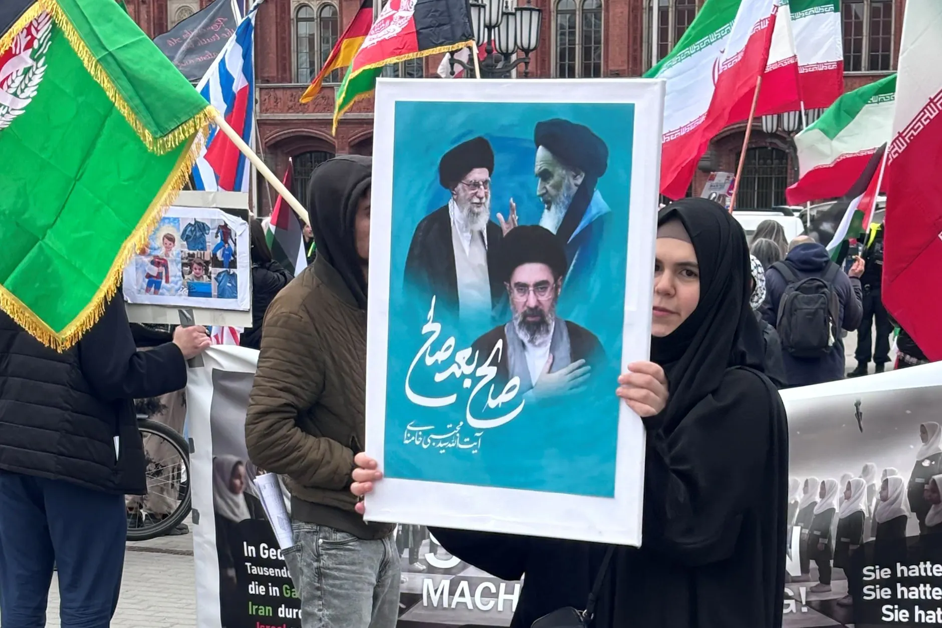 Demonstration am Freitag vor dem Roten Rathaus, dem Amtssitz von Kai Wegner: Eine Frau hält am Freitag ein Plakat mit den bisherigen drei iranischen Religionsführern.