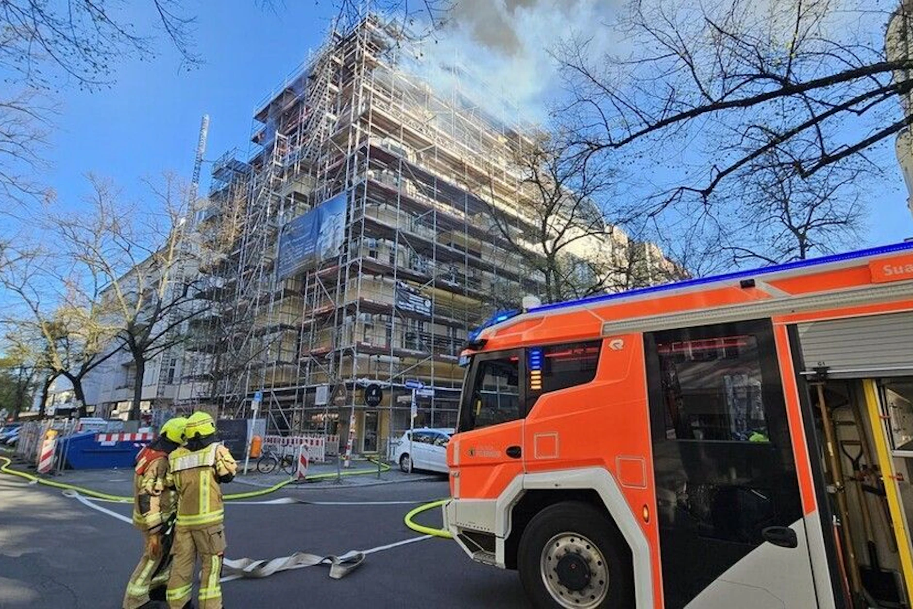 Einsatzkräfte stehen vor dem eingerüsteten Wohnhaus in der Mommsenstraße.