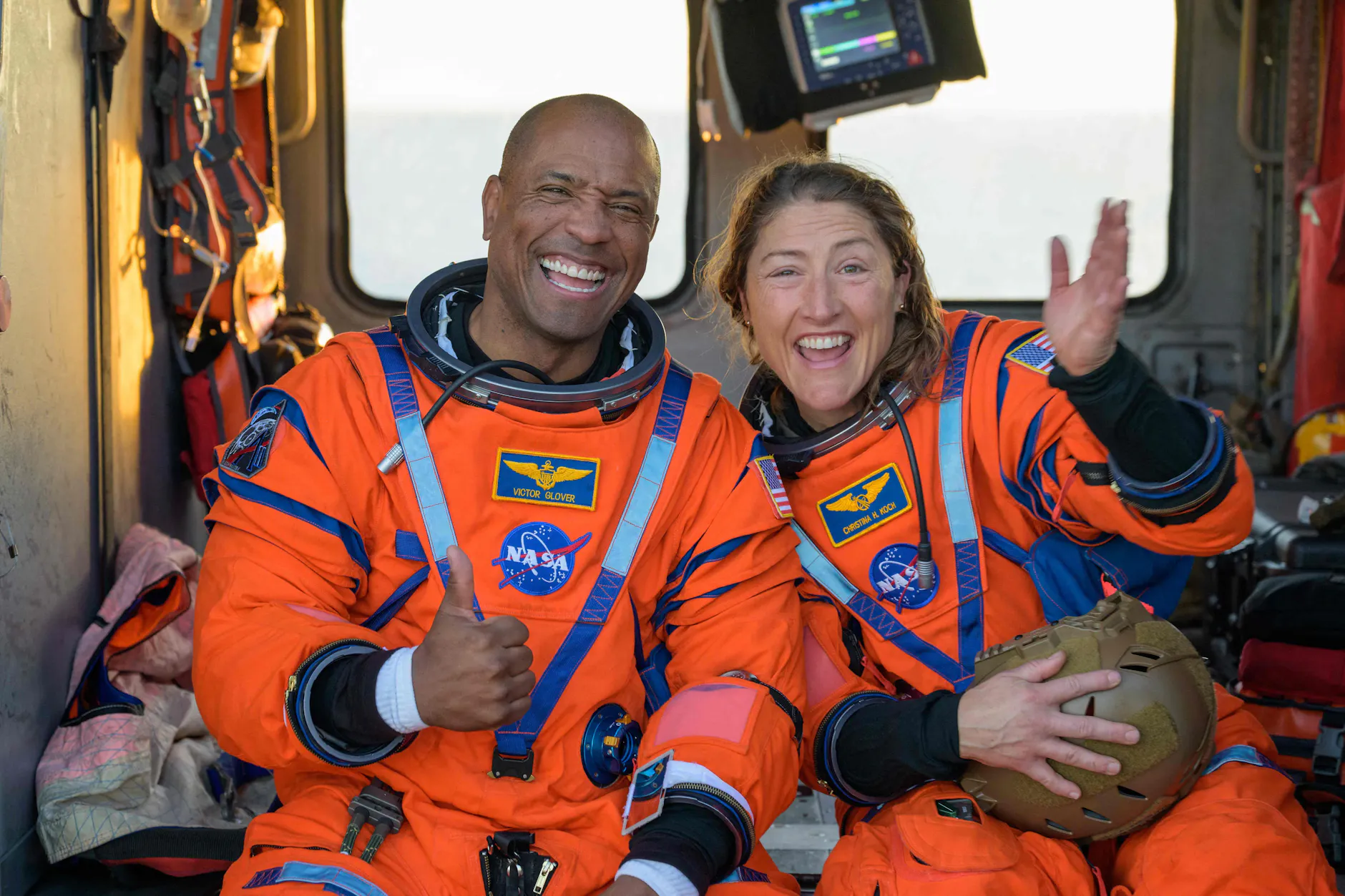 Die Nasa-Astronauten Victor Glover und Christina Koch sitzen nach der Wasserung von Artemis II an Bord eines Hubschraubers auf dem Deck eines Marineschiffs.