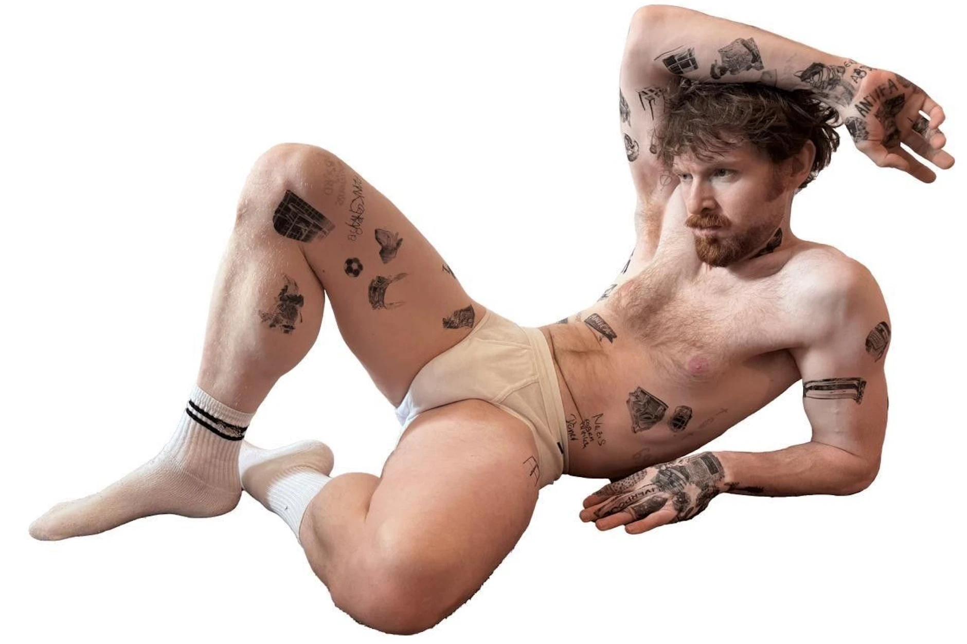 Tätowiertes Modell mit Doppelrippschlüpfer und Tennissocken. Wandbild aus Marc Brandenburgs Werkserie „Tattoos“, 2026, Fotografie
