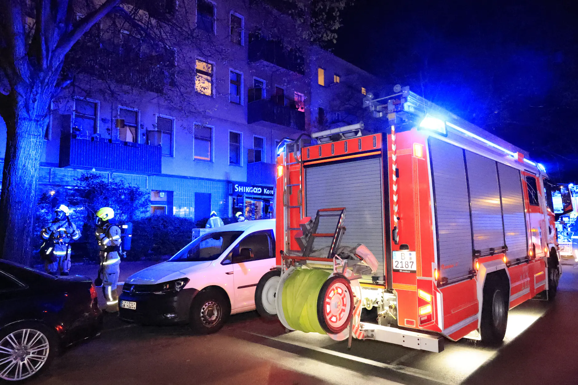 Feuerwehr im Einsatz in Berlin-Wedding: Vor dem Mehrfamilienhaus stehen Einsatzfahrzeuge, während Kräfte unter Atemschutz den Brand bekämpfen.
