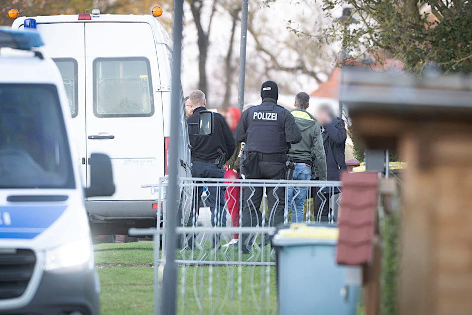 Eine tatverdächtige Frau (Mitte l) verlässt in Begleitung von Polizeibeamten ihr Wohnhaus.