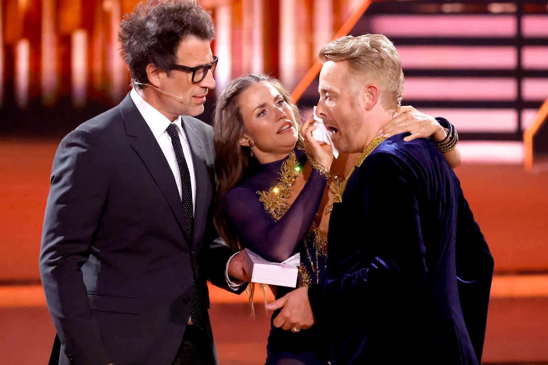 Moderator Daniel Hartwich (l.) und Profitänzerin Mariia Maksina kümmern sich um die blutende Wunde von Ross Antony.