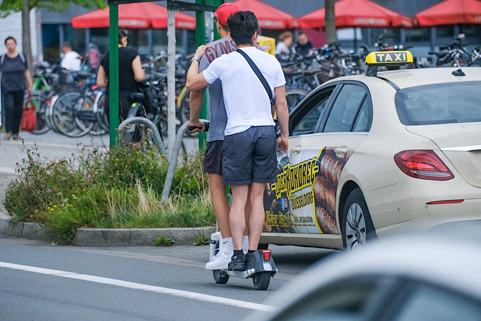 Zwei Personen nutzen unzulässigerweise gemeinsam einen E-Scooter im dichten Stadtverkehr. (Symbolbild)