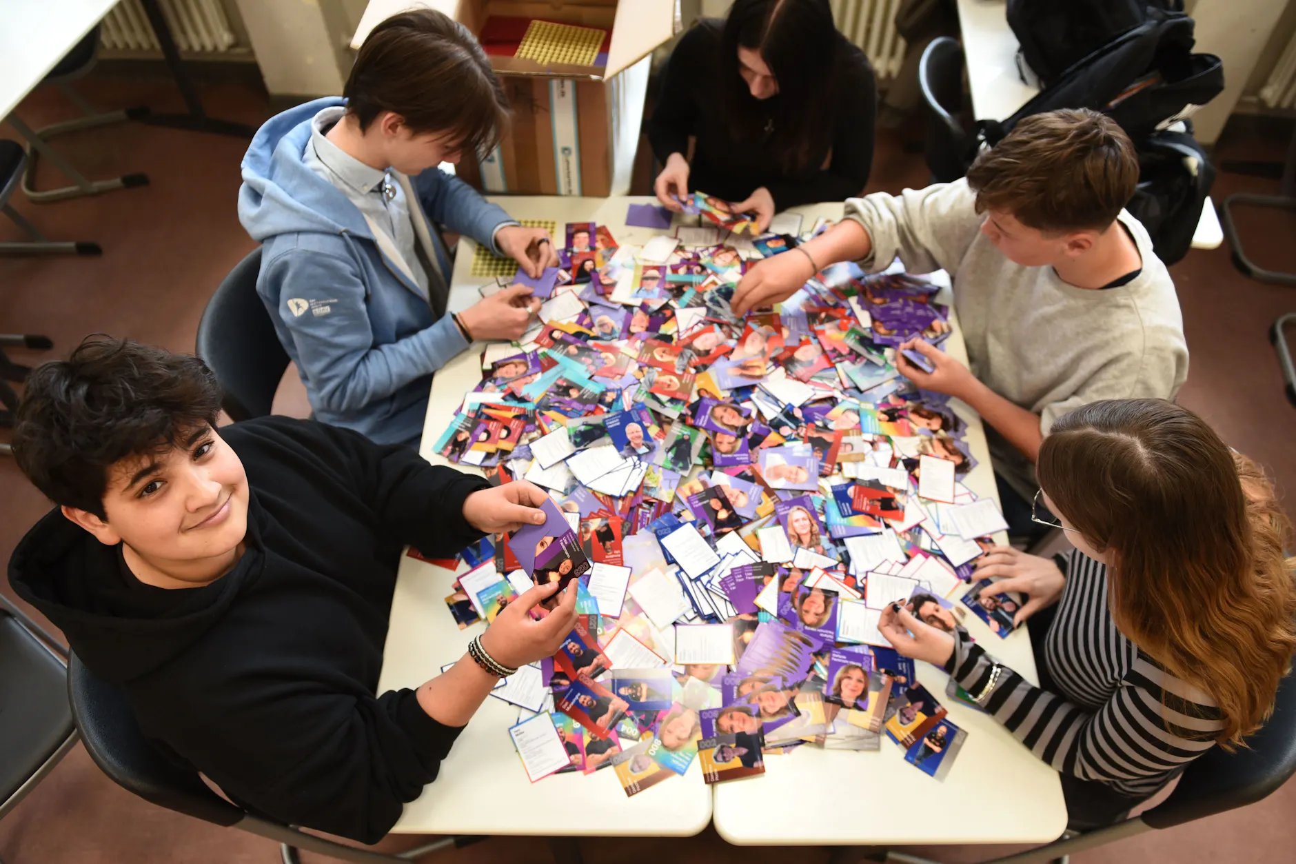 Robin und seine Helfer packen jeweils fünf Lehrer-Sammelkarten in Päckchen zum Verkauf.