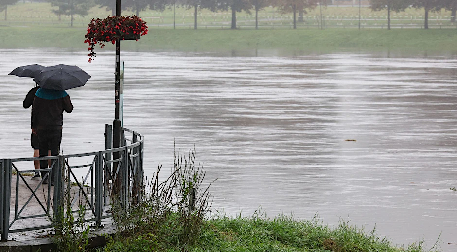 Zwei Männer schauen während steigender Pegelstände auf das Hochwasser der Elbe. Sachsen will nun ausgerechnet beim Hochwasserschutz den Rotstift ansetzen.