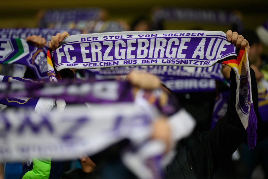 Auch in Krisenzeiten halten Aues Fans ihre Fanschals hoch. Nach 23 Jahren Profifußball stehtnun der Gang in die Regionalliga bevor.
