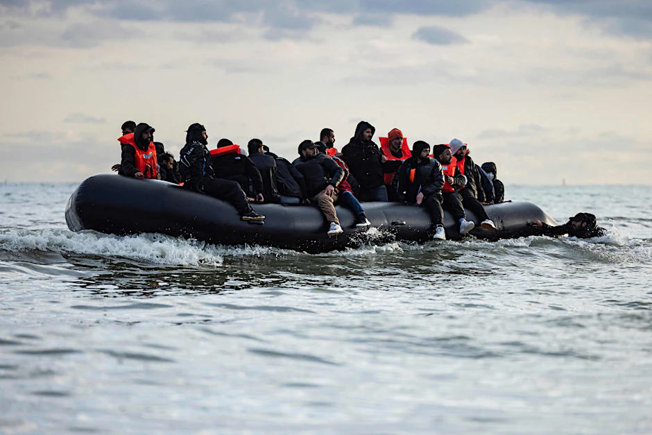 Frankreich, Loon-Plage: Migranten sitzen auf einem Schlauchboot und versuchen, den Ärmelkanal zu überqueren.