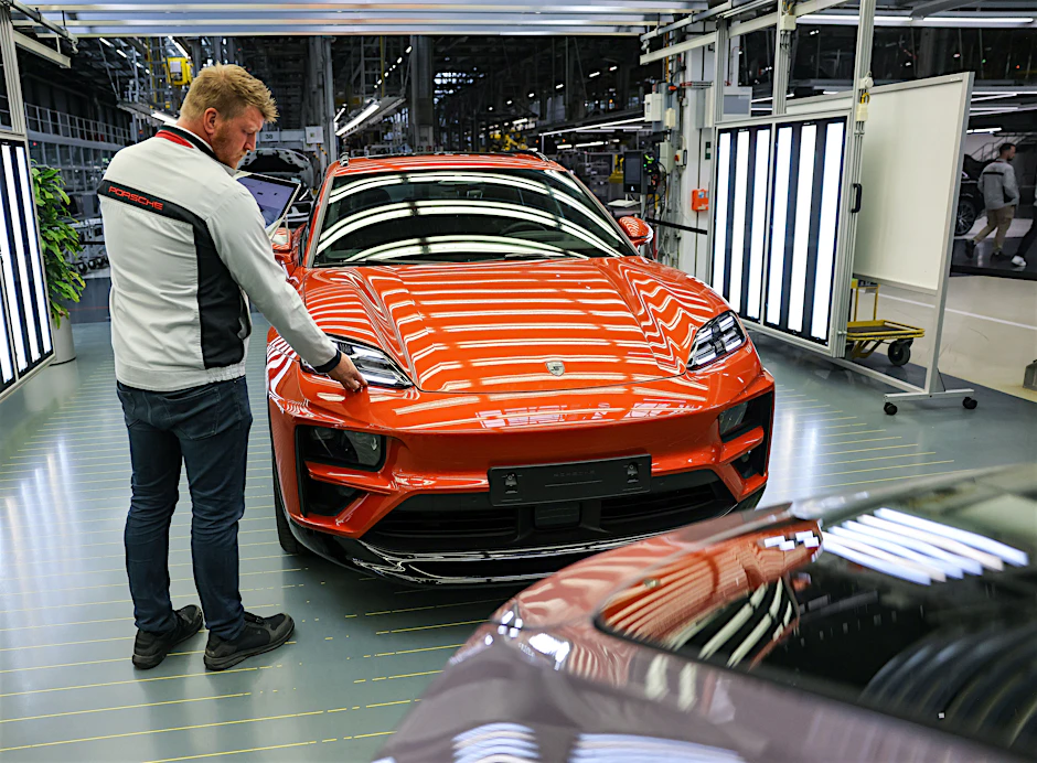 Ein Porsche-Mitarbeiter prüft in der Qualitätskontrolle einen vollelektrischen Porsche Macan im Werk Leipzig. 