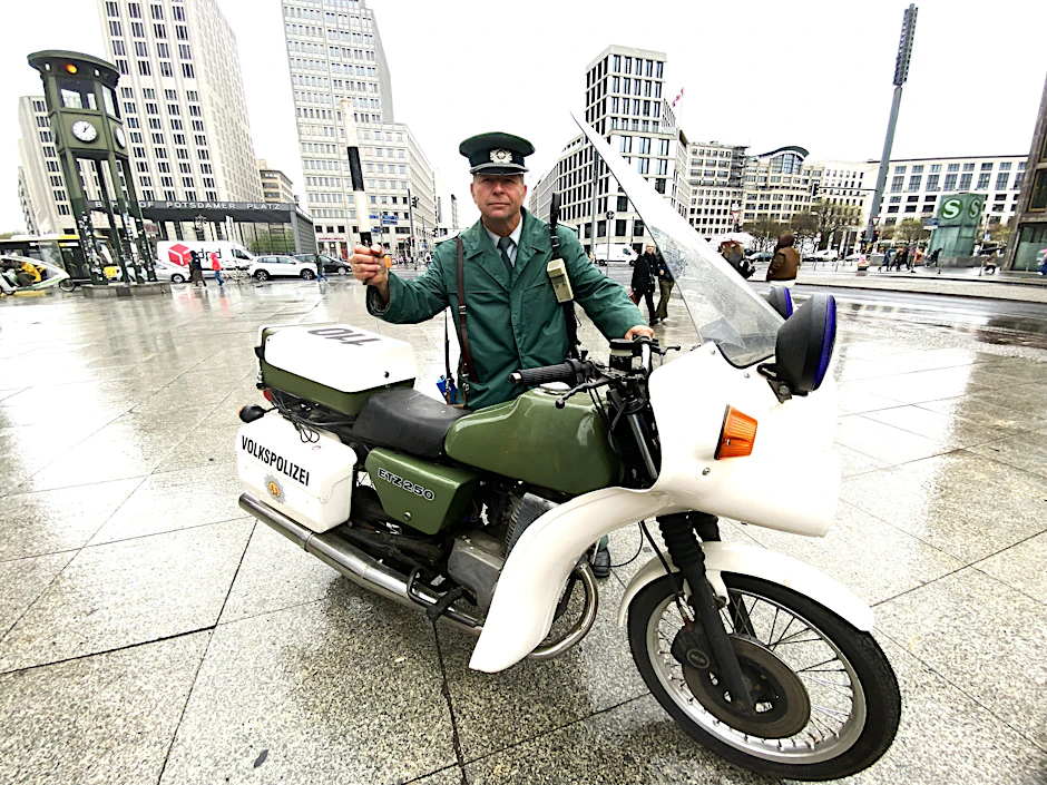 Wo einst die Mauer stand: Die Volkspolizei ist auf dem Potsdamer Platz wieder da. Mit echter Uniform und mit Original-Motorrad lässt Kabarettist Mario Kaulfers (60) ganz in der Nähe die DDR in einer Show aufleben.