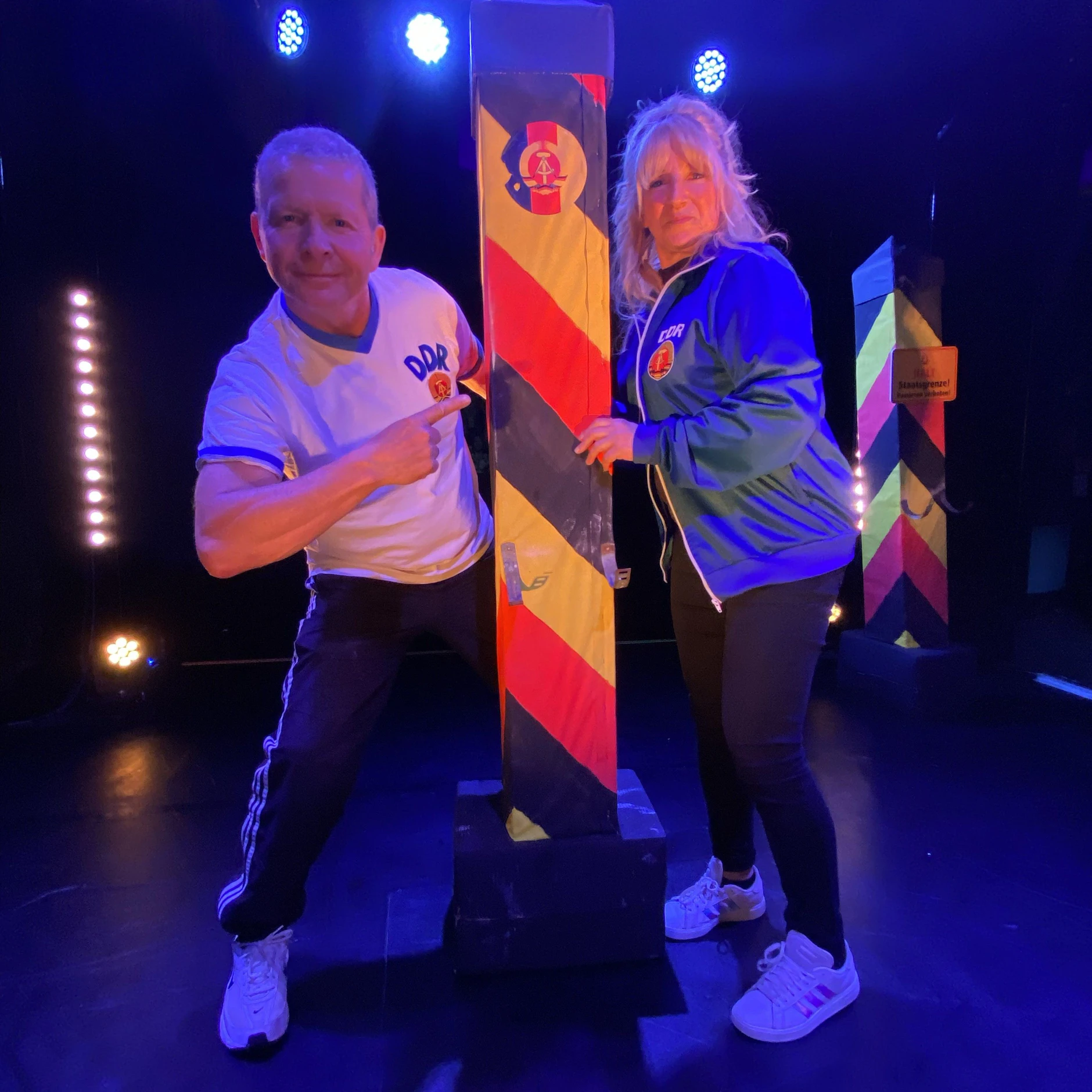 Mario Kaulfers und seine Frau Susanne auf der Bühne mit einem Grenzpfahl der DDR. In der Tat verlief an diesem Ort am Potsdamer Platz die Berliner Mauer.