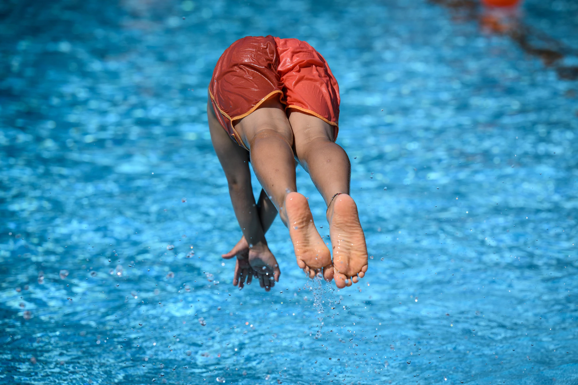 Ein Junge springt ins Schwimmbecken.