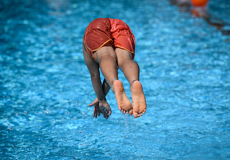 Ein Junge springt ins Schwimmbecken.