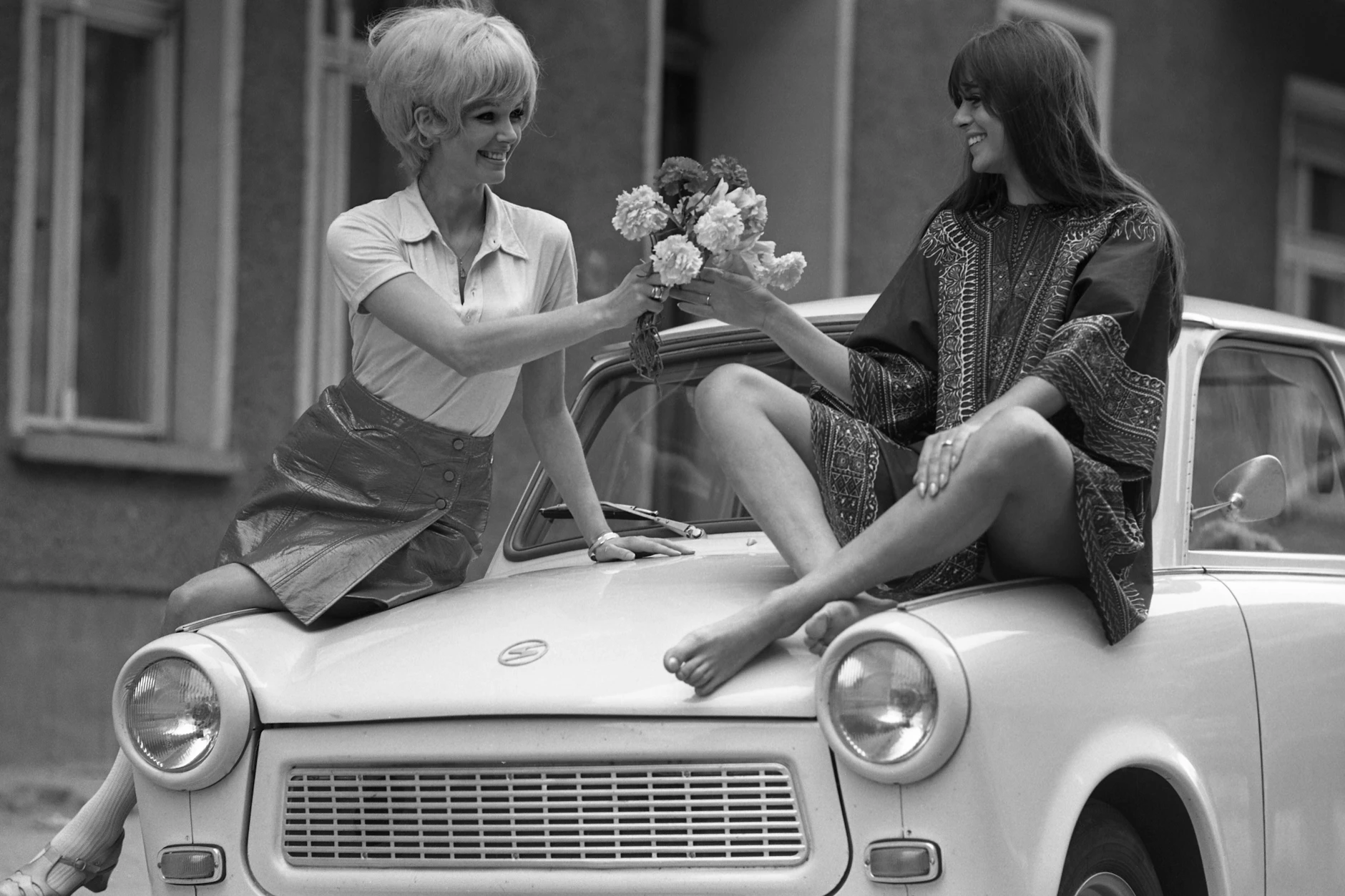 In der DDR gab es noch ein anderes Leben jenseits der SED-Diktatur: Zwei Frauen mit einem Blumenstrauß posieren auf einem Trabi für einen Modefotografen – ein Bild aus den 70er Jahren, das für viele Ostdeutsche auch ein Stück Heimat vermittelt.