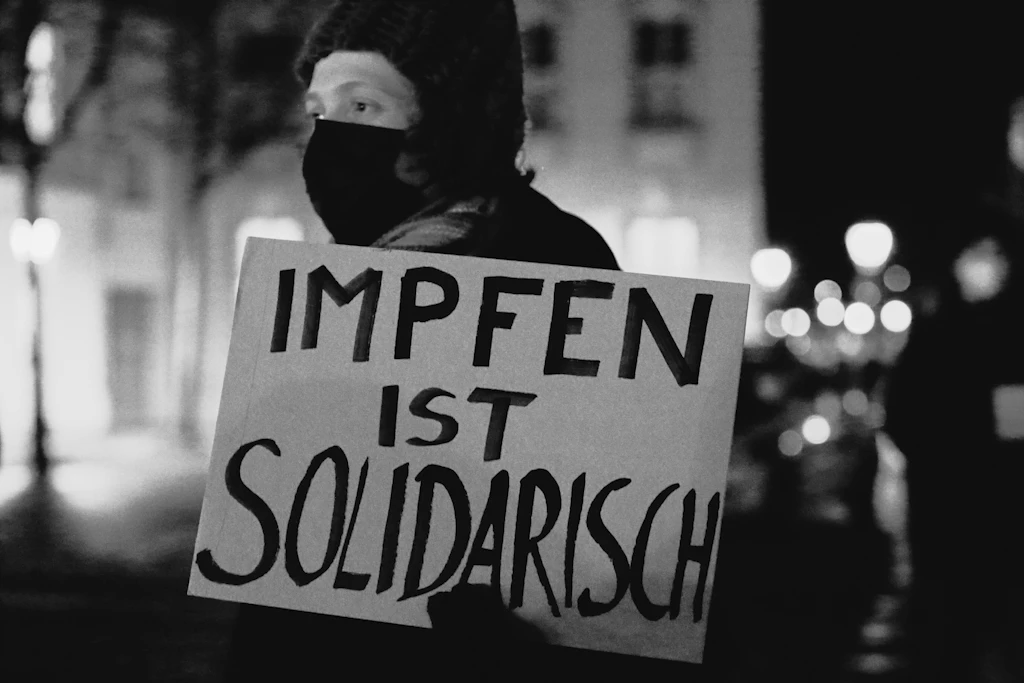 Eine Gegendemonstrantin steht mit einem Schild "Impfen ist solidarisch" während einer Demonstration gegen die Impfpflicht in der Coronavirus-Pandemie am Nauener Tor, Potsdam, 31. Januar 2022.