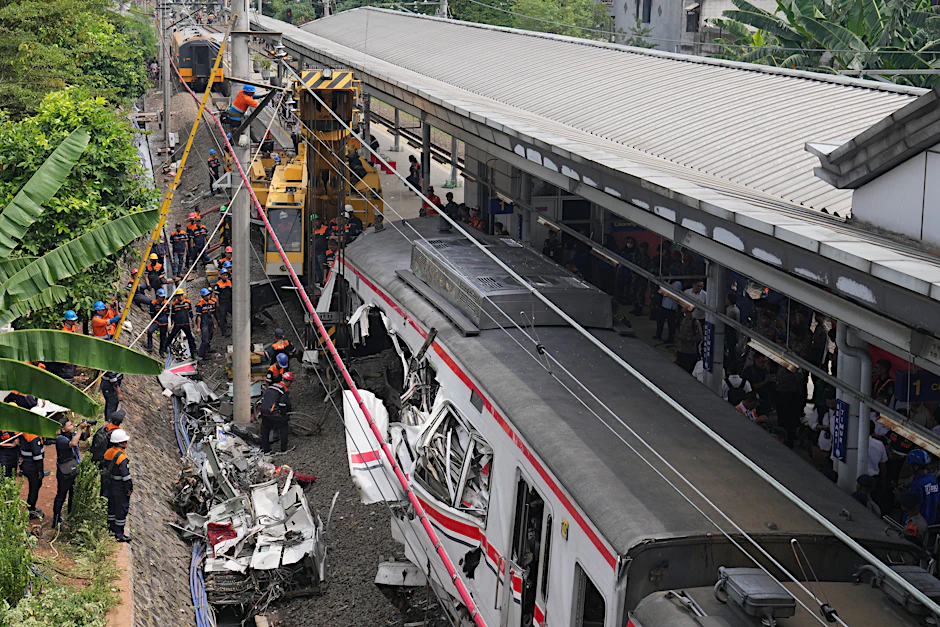 Arbeiter setzen eine schwere Maschine ein, um die Trümmer eines Zuges nach einer Kollision in Bekasi, Indonesien, zu beseitigen.