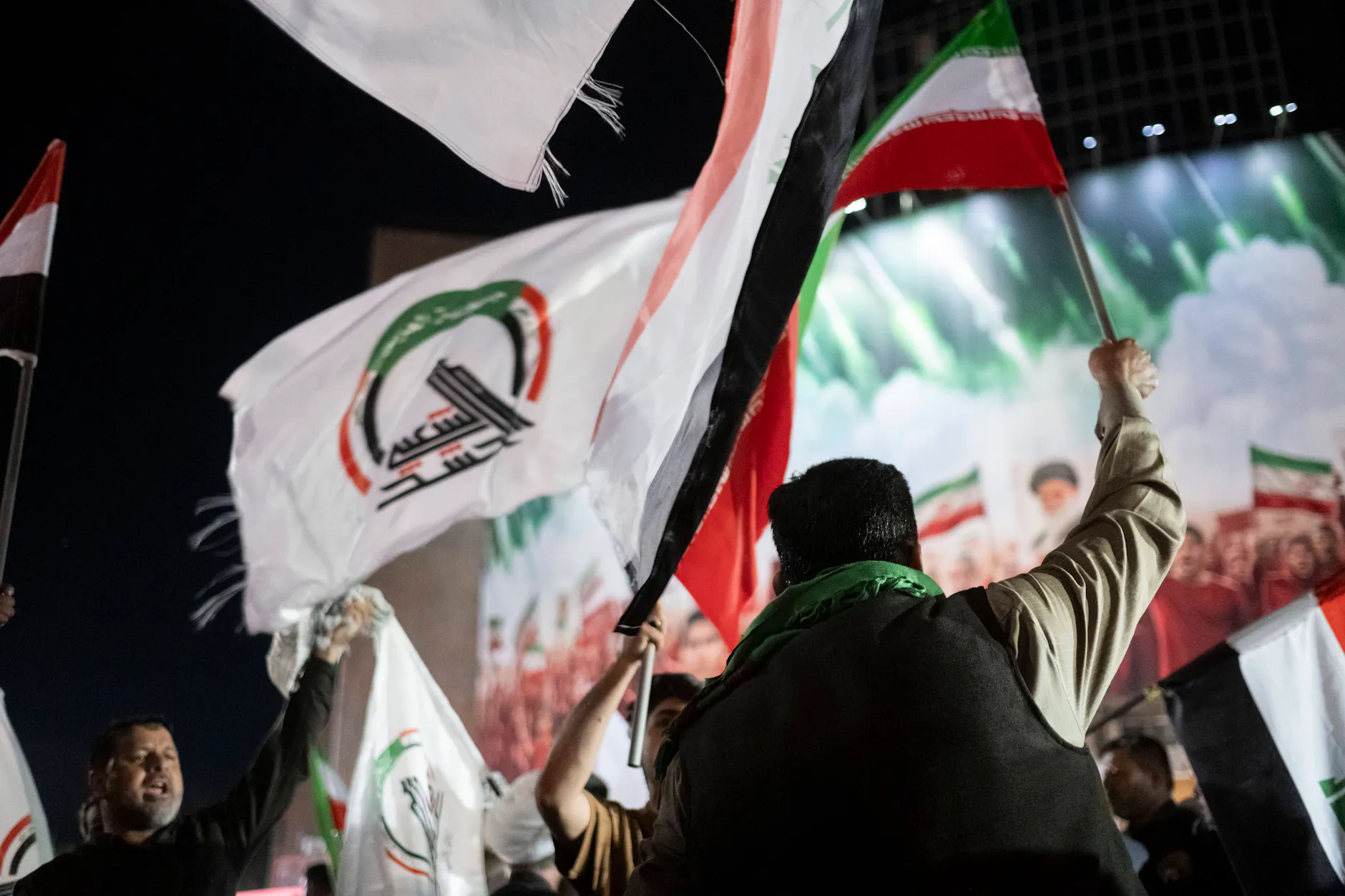 Kämpfer der irakischen Hashd al-Shaabi jubeln mit Flaggen abends in Teheran.