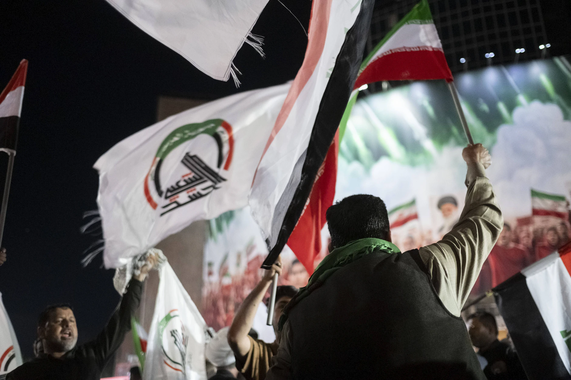 Kämpfer der irakischen Hashd al-Shaabi jubeln mit Flaggen abends in Teheran.