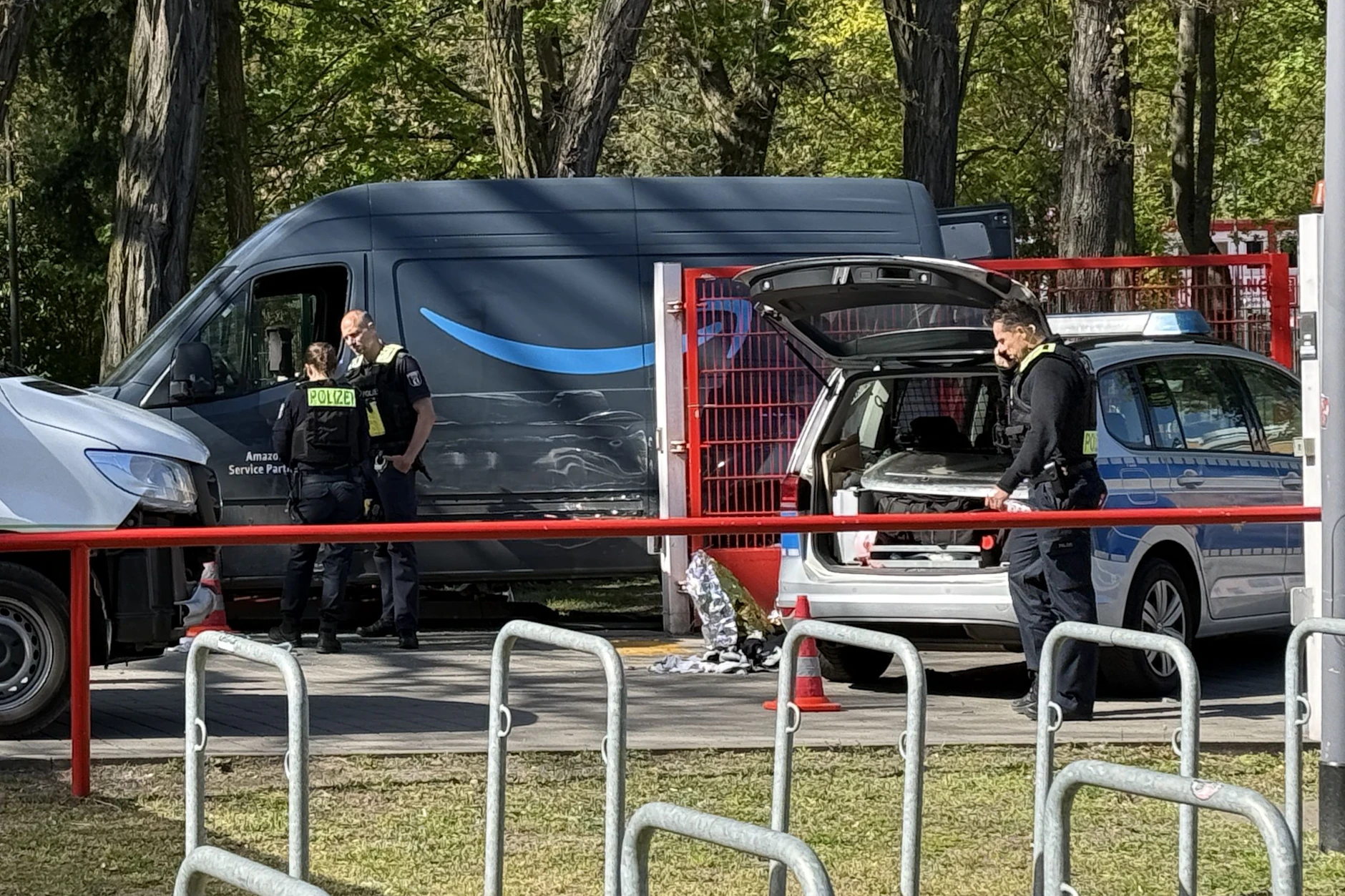 Das gestohlene Amazon-Lieferfahrzeug und ein Polizeifahrezug stehen nach der Tat am Parkplatz der Alten Försterei.