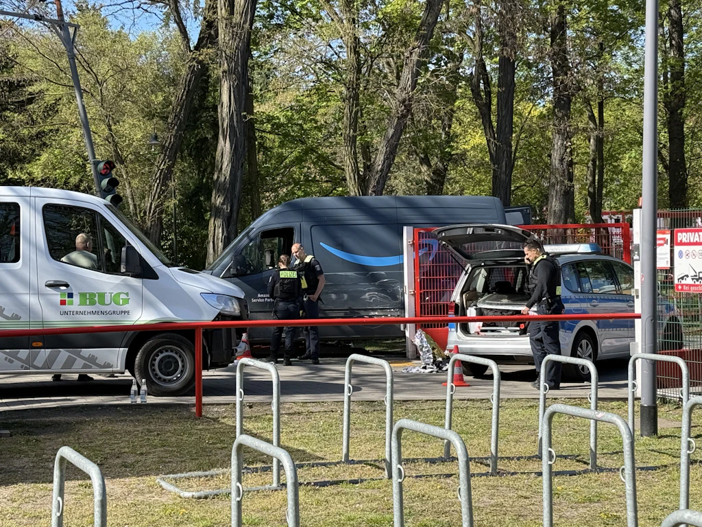 Das gestohlene Amazon-Lieferfahrzeug und ein Polizeifahrezug stehen nach der Tat am Parkplatz der Alten Försterei.