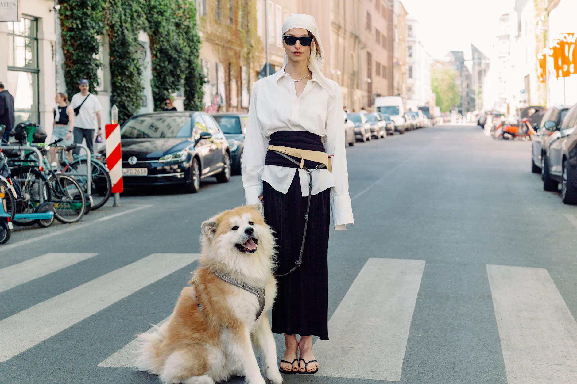 Sie habe sich nur eben zum Gassigehen mit ihrem Hund Yūgen etwas Bequemes angezogen, erzählt Eliza - doch bei diesem Look wird selbst die Leine zum Teil des Gesamtkonzepts. Über das Vintage-Hemd hat sie ein Bandeau-Top von Wolford gezogen und zum Korsett umfunktioniert, darüber eine cremefarbene Gürteltasche. Der plissierte Rock ist ein Vintage-Fund von Issey Miyake, die schwarzen Flip-Flops von Havaianas und die Sonnenbrille von Ray-Ban.